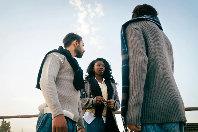 Three people talking outdoors on a sunny day.